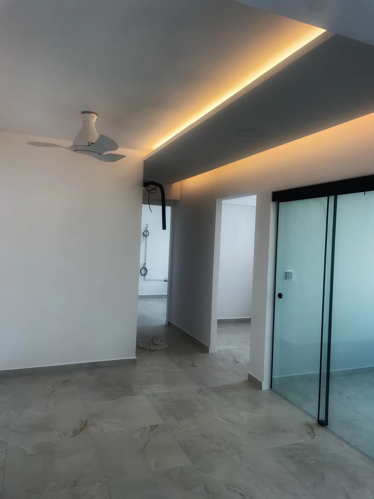 A bedroom walkway in a Singapore apartment featuring a false ceiling with covelighting to provide a soft, ambient glow that defines the path