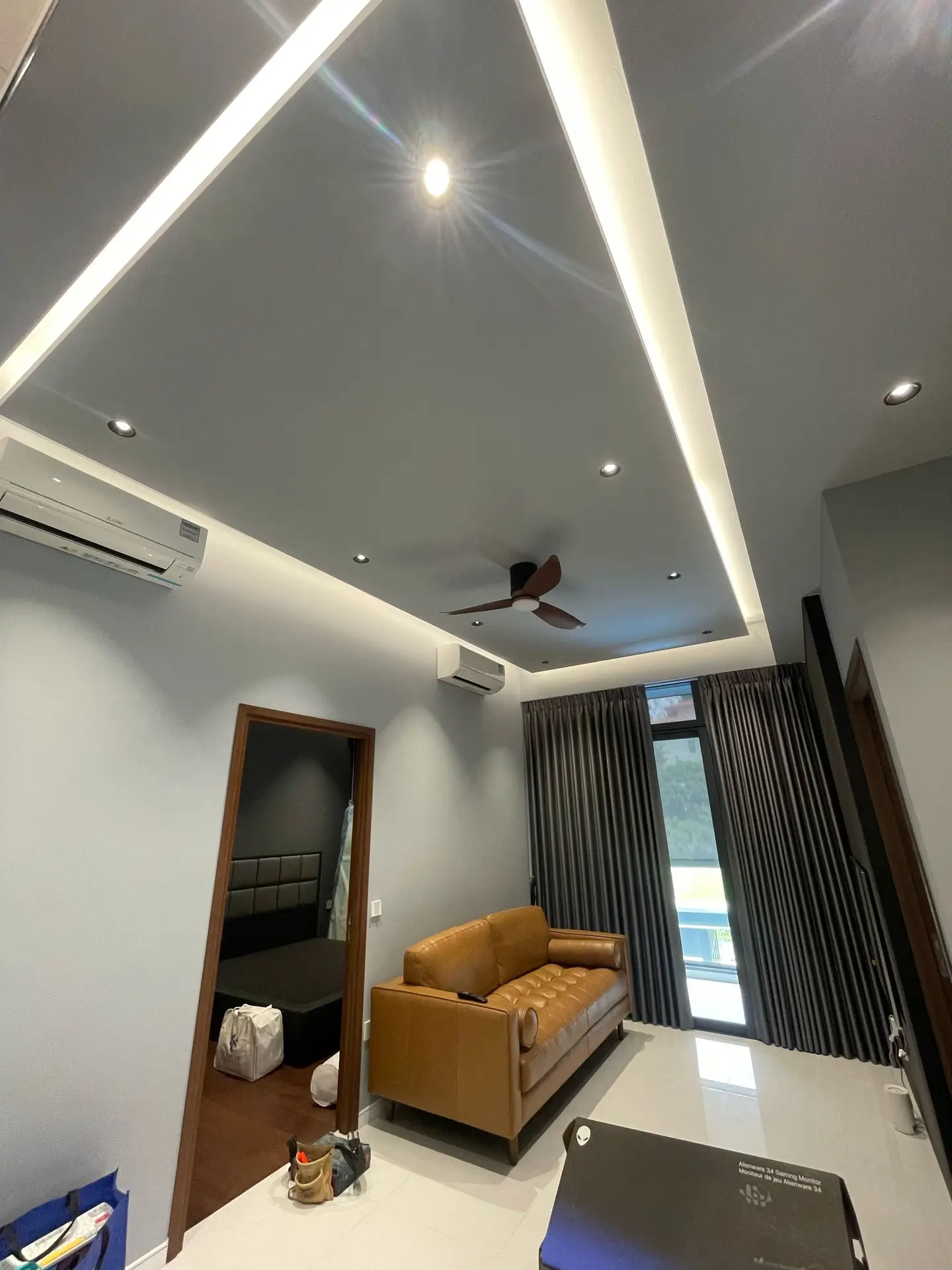 A modern living room at Phoenix Residences featuring a rectangular island false ceiling with soft, indirect cove lighting, creating a stylish floating effect.
